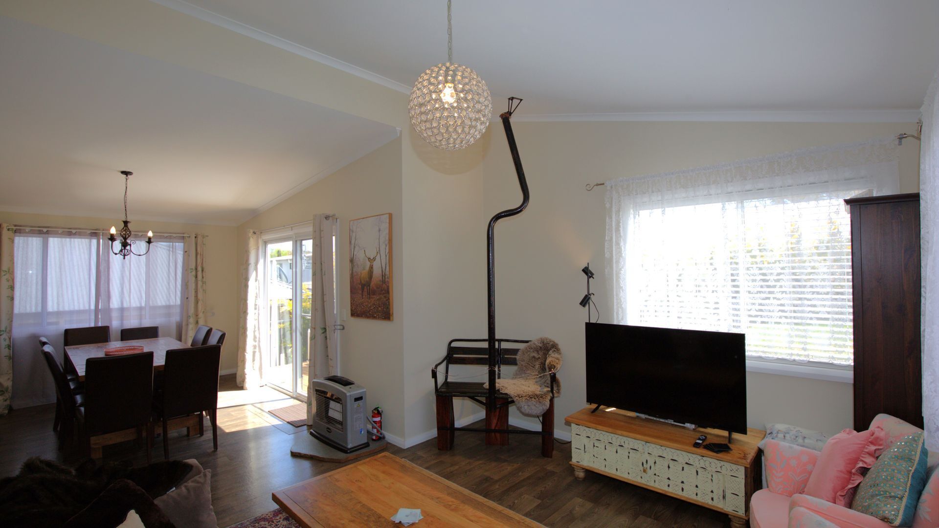 Una sala de estar con comedor, chimenea, televisor y un ventanal con persianas.
