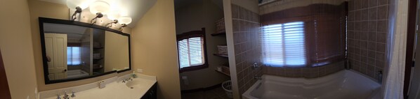 A bathroom with a large mirror, a sink, and a bathtub.