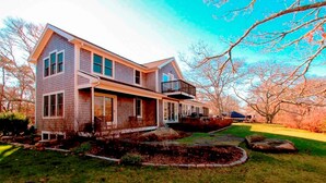 A two-story house with a front porch, a covered entryway, and a visible garage. - Menemsha Home Fully Renovated w/ Amazing Waterview's of Vineyard Sound (Menemsha)