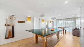 A modern living room with a pool table, billiards rack, and a sofa.