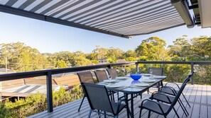 Eine Terrasse mit Esstisch, mit Blick auf eine Wohngegend mit Bäumen und Häusern.