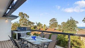 Ein Balkon mit Grill, Esstisch, Stühlen und Blick auf die Nachbarschaft.