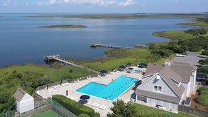 Ein großer Pool mit Blick auf einen See und eine Anlegestelle.
