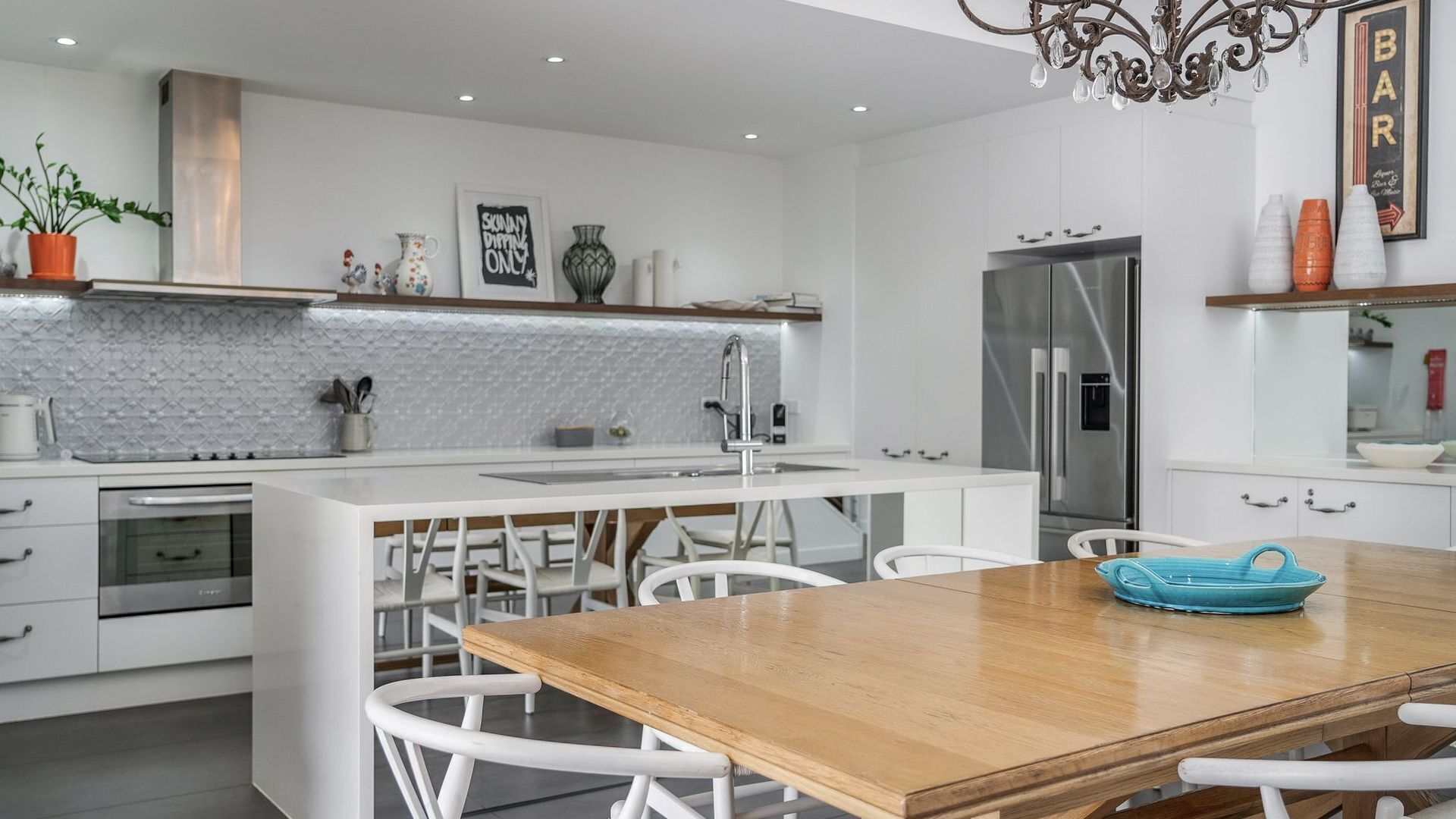 Una cucina moderna con mobili bianchi, un tavolo da pranzo in legno e un frigorifero in acciaio inossidabile.