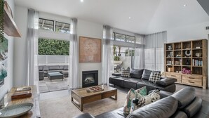 A modern living room with a fireplace, a sofa set, a coffee table, and a bookshelf.