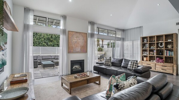 Una sala de estar moderna con chimenea, un conjunto de sofá, una mesa de centro y una estantería.