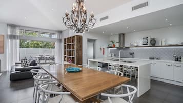 A modern kitchen with white cabinetry, a central island, and a dining area with a wooden table and white chairs.