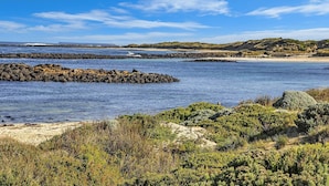 A coastal landscape with rocky outcrops, sandy beaches, and green vegetation. - Hearns Beachside Villa  7 (Port Fairy)