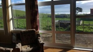 A room with large windows offering a view of a green landscape and a fence.