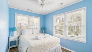 A bedroom with a bed, two bedside tables, a ceiling fan, and two windows with blinds. - Blue Sky | Two Units | Pool w/Heating Option | Across from Beach Access (Folly Beach)