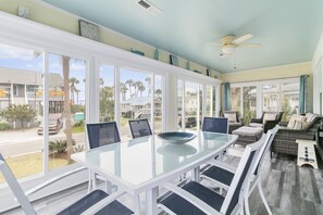 Relax in this spacious room with a dining table, sofa, and armchairs, offering a view of the outside through large windows.