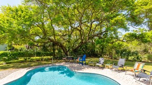 A swimming pool with lounge chairs and a large tree in the background. - Blue Sky | Two Units | Pool w/Heating Option | Across from Beach Access (Folly Beach)