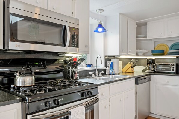 A modern kitchen with stainless steel appliances, a gas stove, a microwave, and a built-in oven. - Romatic Beach Cottage | Easy Beach Access, Fireplace, 10 Mins to Santa Barabara (Montecito)