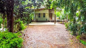 A building with a covered entrance, a gravel driveway, and surrounding greenery. - 15 Esprit Drive - Rainbow Shores. Wifi. Close to beach (Rainbow Beach)
