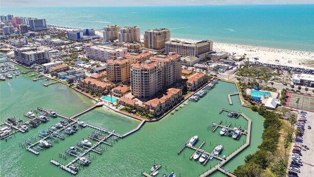 An aerial view of a coastal city with a marina, high-rise buildings, and a beach.