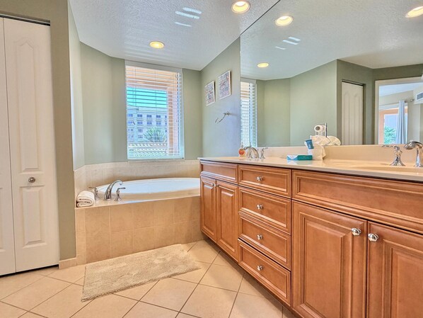A bathroom with a bathtub, vanity, and a large mirror.