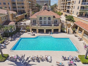 A large swimming pool surrounded by lounge chairs and palm trees, with multi-story buildings in the background. - Belle Harbor 401W Belle Harbor Jewel (CLearwater Beach)