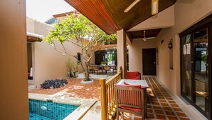 A covered outdoor area with a pool, wooden furniture, and a ceiling fan.
