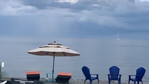 Een zitgedeelte aan het strand met een tafel, stoelen en een parasol.