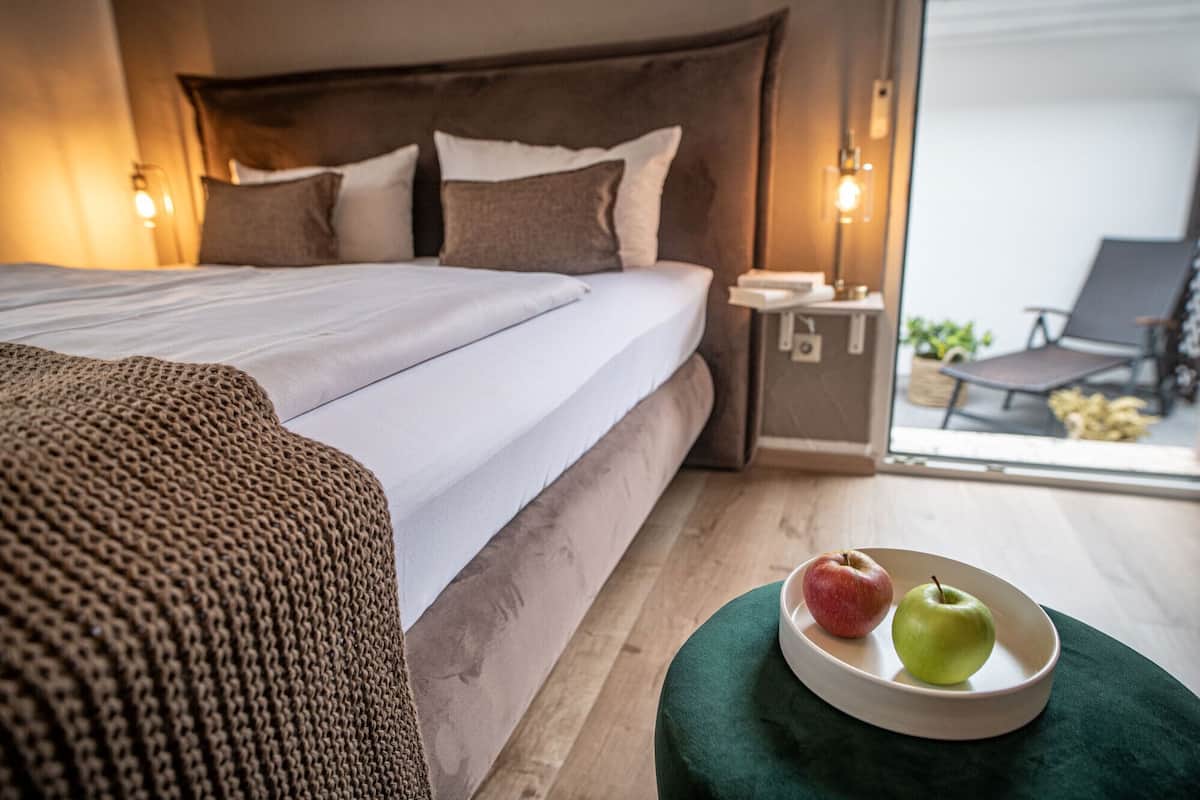Une chambre à coucher avec un lit, une table de chevet et une vue sur l’extérieur.