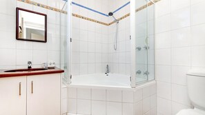 A bathroom with a glass-enclosed shower, a vanity with a mirror, and a toilet. - Shearwater House - Riverfront Accommodation (Port Fairy)