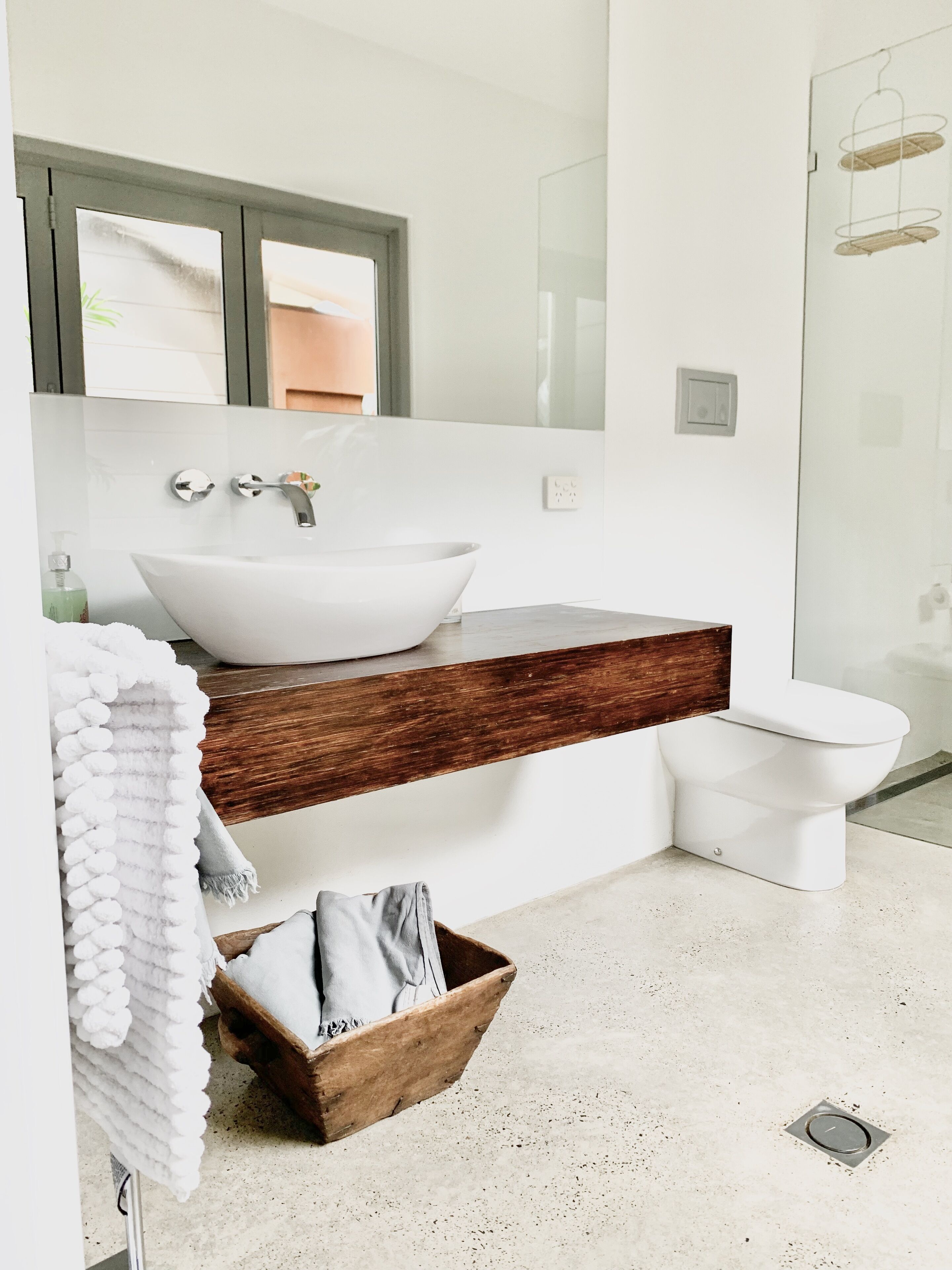 A modern bathroom with a white sink, wooden vanity, and a toilet.