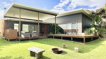 A modern house with a covered patio, a dining area, and a well-maintained lawn.