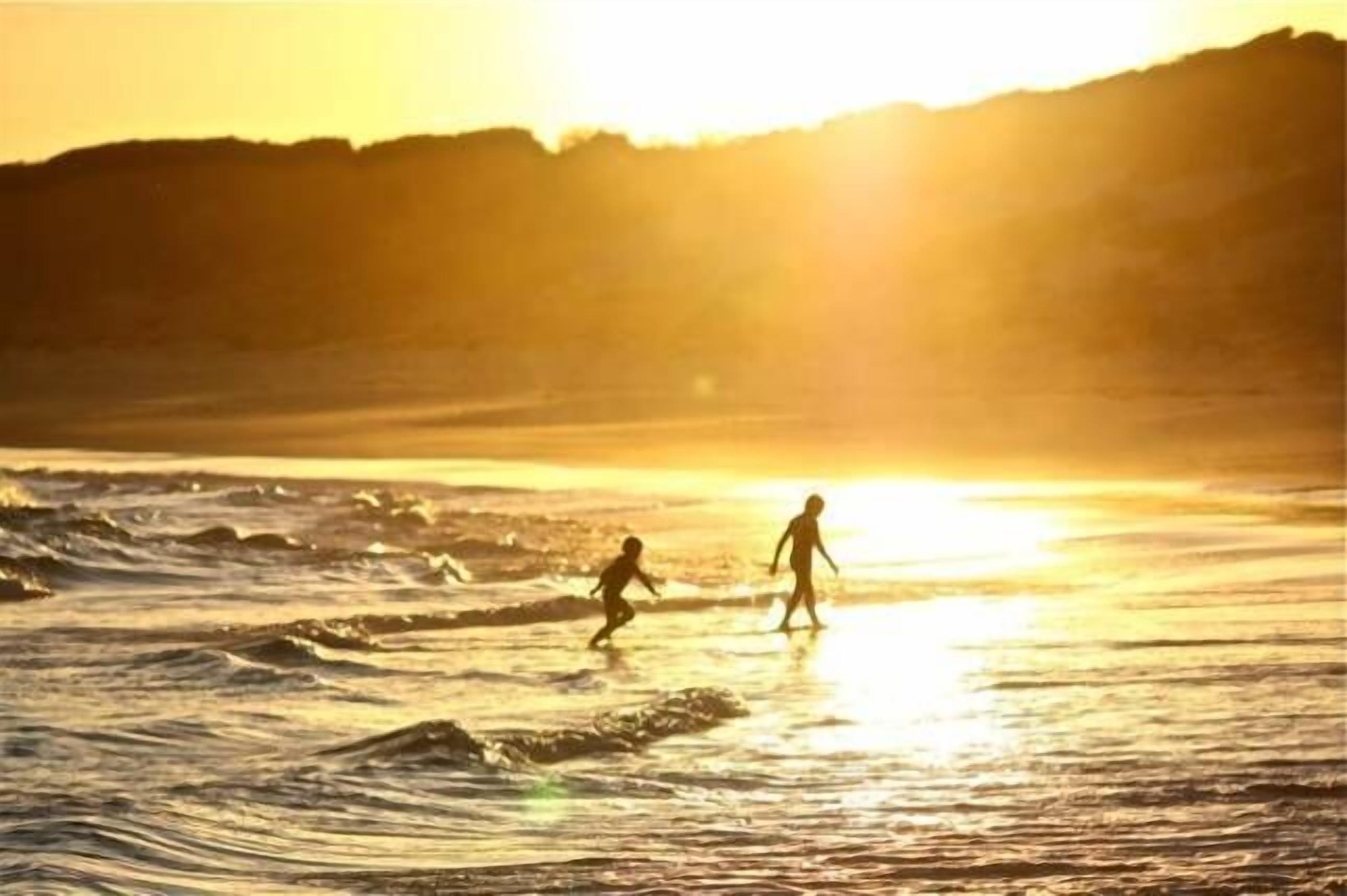 Une scène de plage avec des vagues et un coucher de soleil.