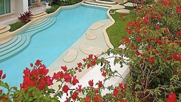 Ein Resort mit mehreren weißen Gebäuden, einem Swimmingpool und roten Blumen.