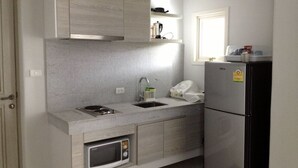 Eine kleine Küche mit einer eingebauten Mikrowelle, einem Spülbecken und einem Kühlschrank.