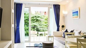 Ein Hotelzimmer mit Balkon, Fernseher, Sofa, Esstisch und einem kleinen runden Tisch.