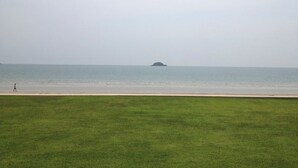Eine grüne Wiese mit Blick auf das Meer und eine kleine Insel in der Ferne.