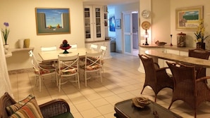 Un coin repas avec une table ronde et des chaises, une cuisine à l’arrière-plan et un salon avec un canapé et une table basse.
