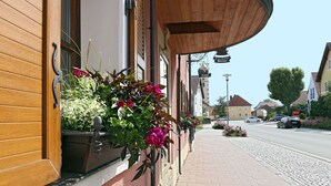 A street view with a building featuring a wooden door and a window with a flower box. - Hotel & Brauereigasthof Püttner (Schlammersdorf)