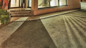 A modern building with a glass facade, a visible staircase, and a set of steps leading to the entrance. - Hotel & Brauereigasthof Püttner (Schlammersdorf)
