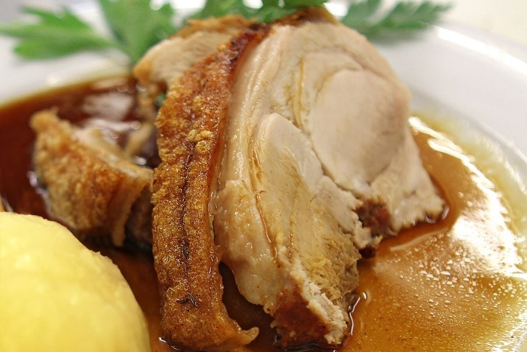 A close-up of a roasted pork dish with gravy and mashed potatoes.