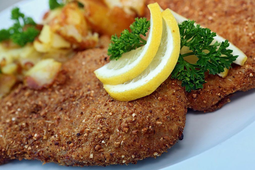 A plate with a breaded cutlet, lemon slices, and parsley garnish.