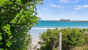 A beach with clear blue water, a sandy shore, and a lighthouse in the distance. - Beachfront - elevated ocean views (Port Fairy)