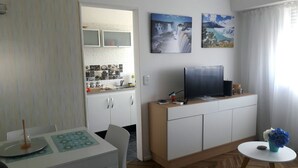 Un ambiente abitativo compatto con angolo cottura, zona pranzo e TV su un mobile.