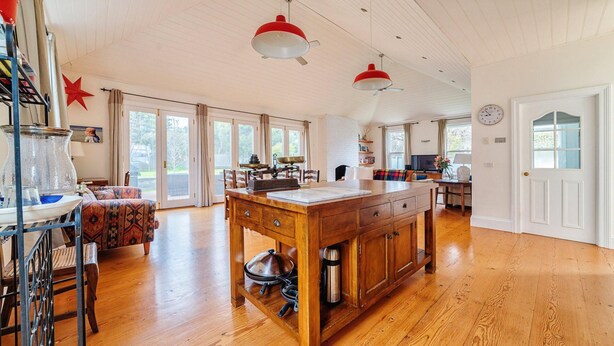 A spacious kitchen with wooden flooring, a central island, and modern pendant lighting. - Kinsale Cottage - perfect central location (Port Fairy)