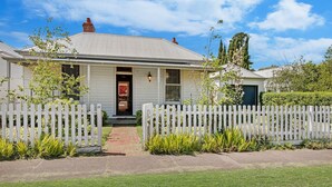 A single-story house with a front porch, a picket fence, and a brick pathway leading to the entrance. - Kinsale Cottage - perfect central location (Port Fairy)