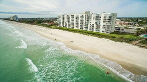 Un hotel frente a la playa con varios pisos, una playa de arena y vista al océano.