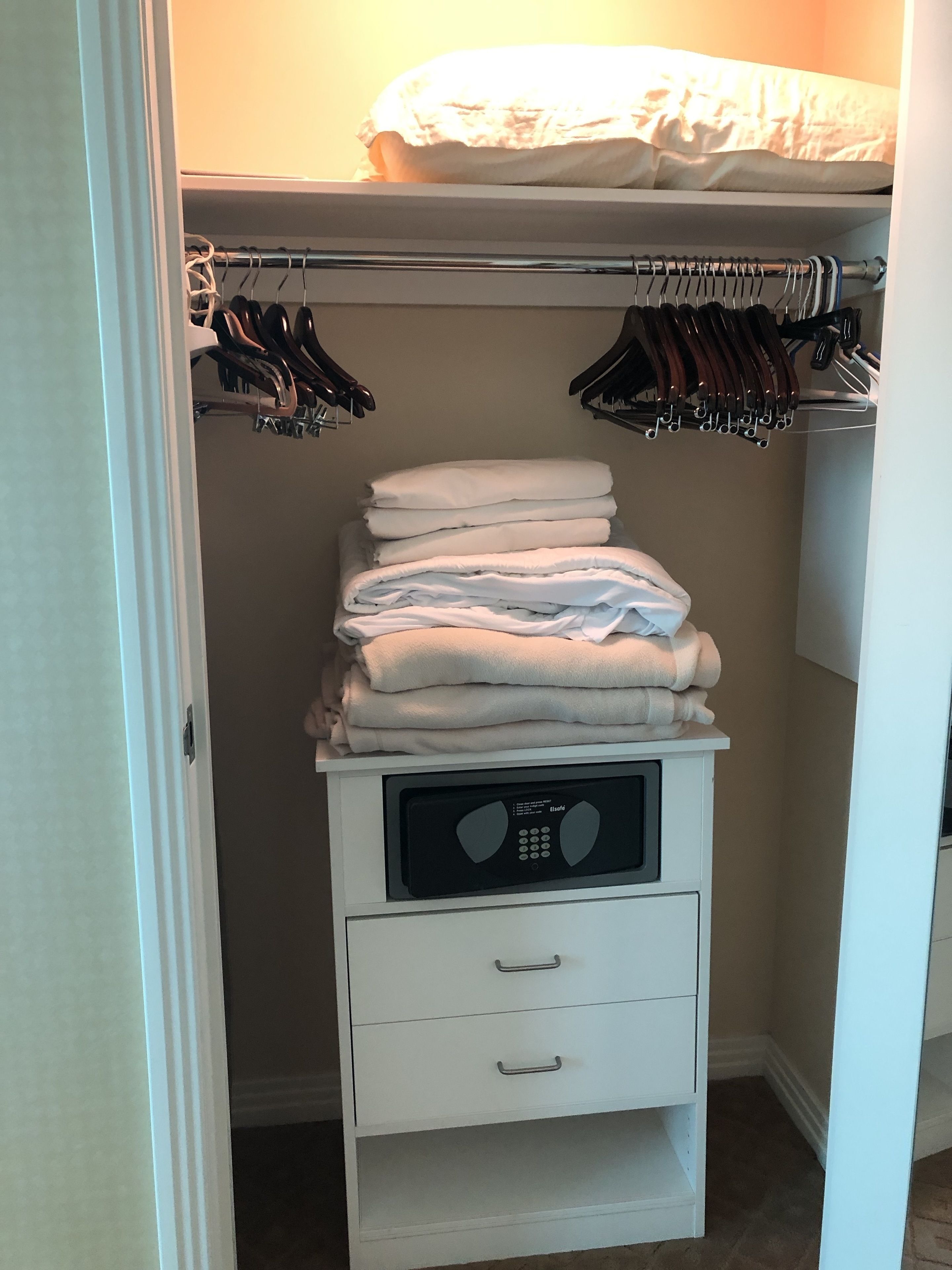 Un dressing avec une tringle à vêtements, une étagère pour ranger les affaires pliées et un micro-ondes encastré.