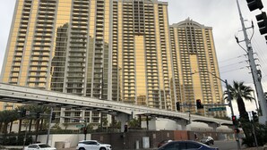 A high-rise building with multiple floors, a pedestrian overpass, and traffic lights. - True 1BR  Strip View at MGM Signature (Las Vegas)