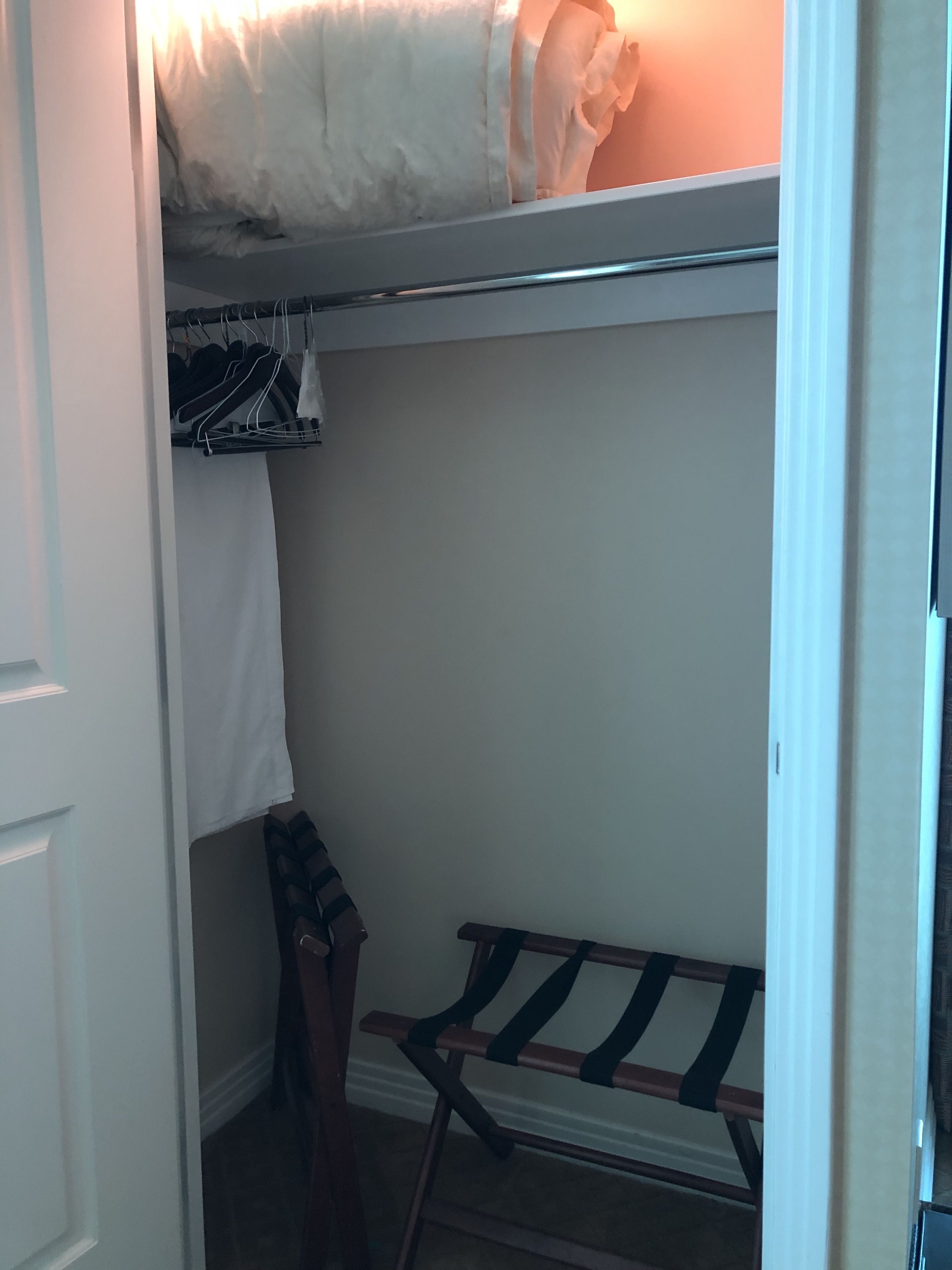A walk-in closet with a hanging rack, a bench, and a door.