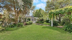 A well-maintained garden with a stone wall, a gazebo, and a variety of trees and shrubs.