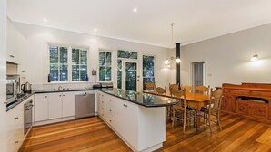A modern kitchen with white cabinetry, a central island, and a dining area with wooden chairs and a table.