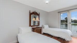 A bedroom with two beds, a dresser, a mirror, and a view of a lake. - The Moorings - Absolute River Frontage (Port Fairy)