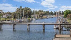 A marina with boats docked, a bridge, and houses in the background. - The Moorings - Absolute River Frontage (Port Fairy)