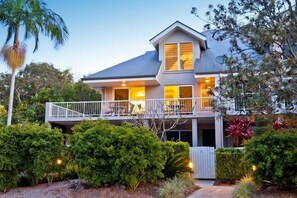 A two-story house with a balcony, surrounded by lush greenery and palm trees. - Byron Bay Beach Apartment BELONGIL BEACH (Byron Bay)